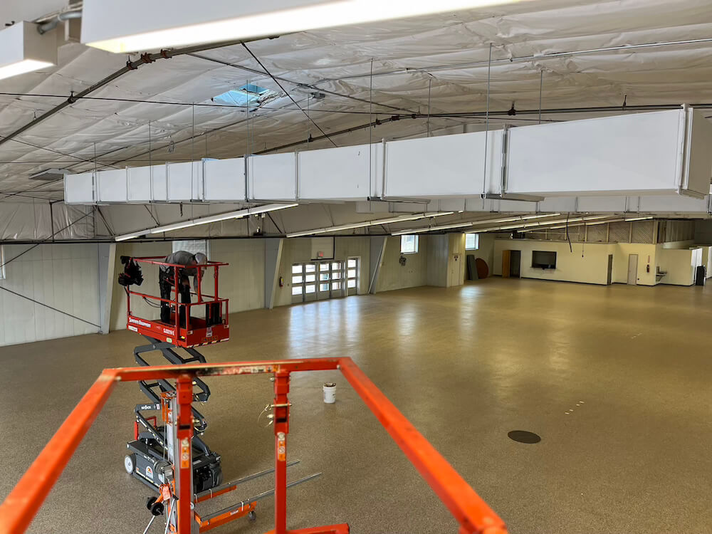 people working on an hvac unit in an empty building