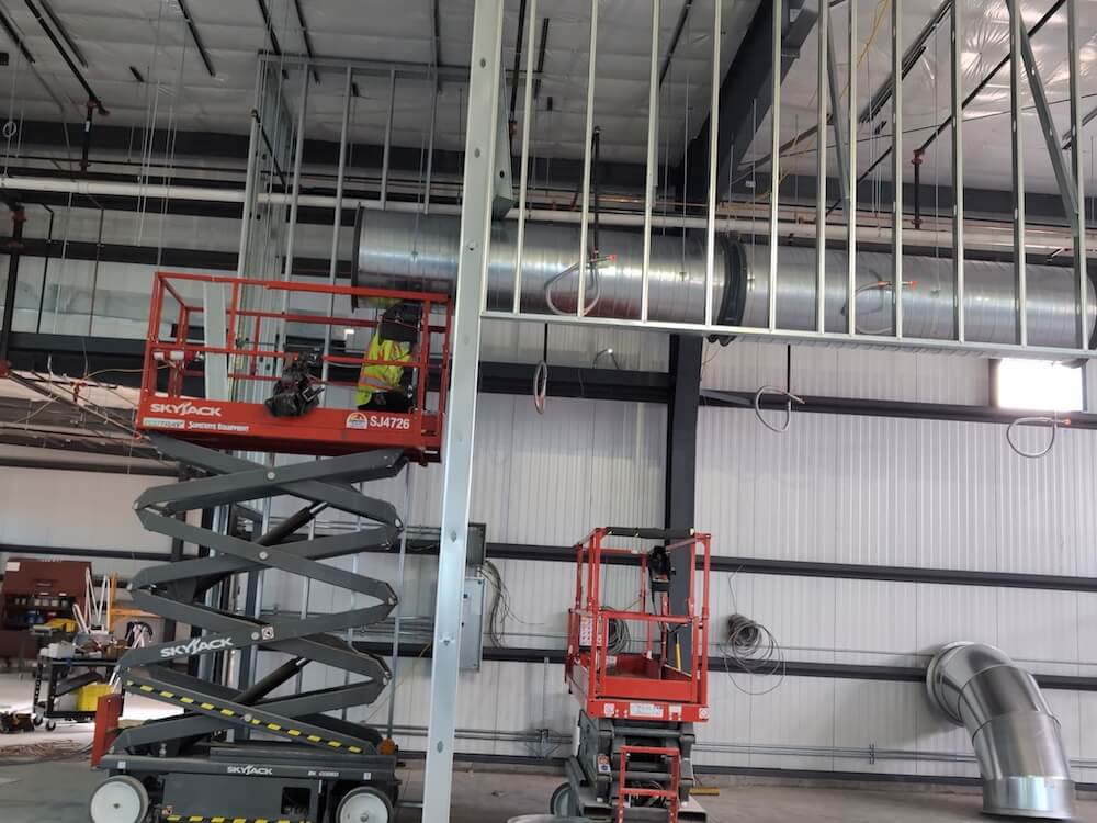 people working on an hvac unit in an empty building